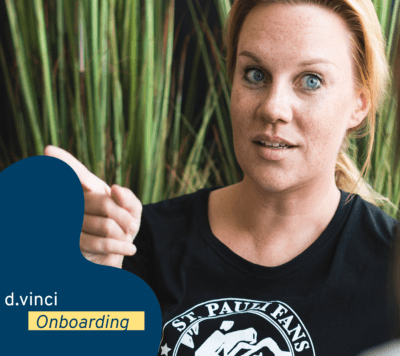 Ein Foto zeigt unsere Mitarbeiterin Laura, die gestikuliert und einen offenen Gesichtsausdruck hat. Das Bild ist geschmückt mit einer dunkelblauen Welle, dem d.vinci-Logo und dem Schriftzug "Onboarding". 